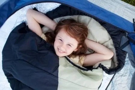 Smiling little girl lying in a sleeping bag