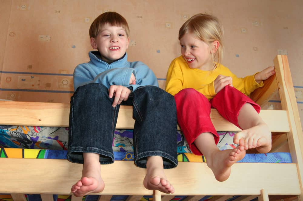 Two siblings chatting on the top bunk bed