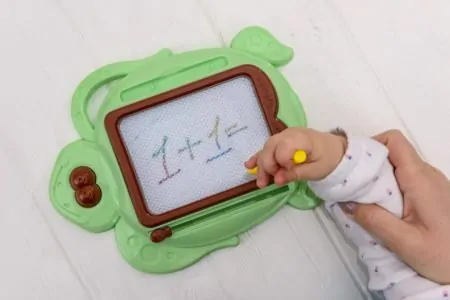Toddler doodling on a magnetic drawing board