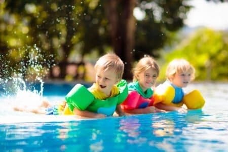 Kids playing in swimming pool with each wearing a swim vest