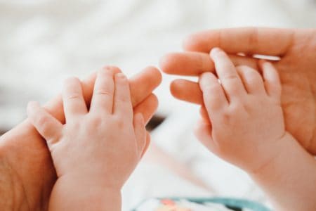 Cute newborn baby holding mother's hands