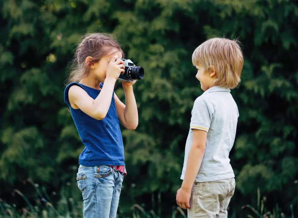 Older sister takes a photo of her brother
