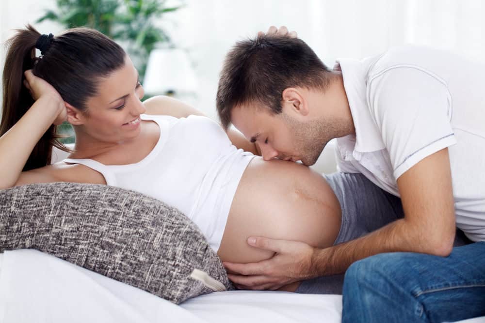 Future dad kissing his wife's pregnant belly