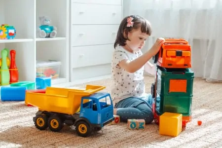Little girl playing with toy garbage trucks