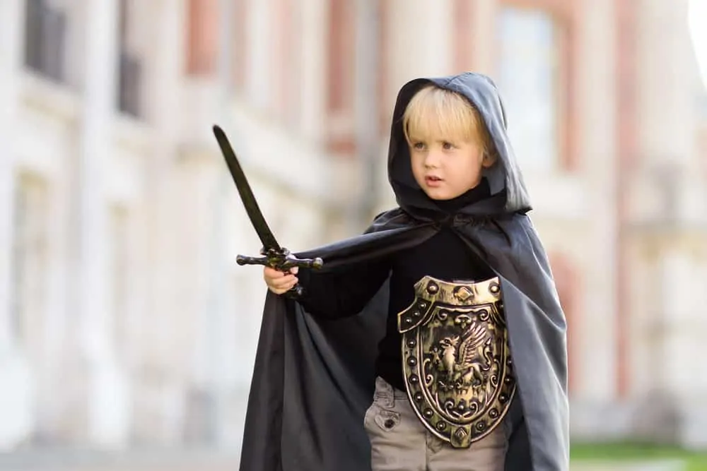 Cute little boy dressed as a medieval knight with sword and shield