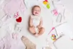 Cute baby surrounded by baby stuff