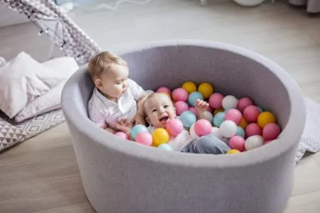 Little cute happy kids play with balls in ball pit