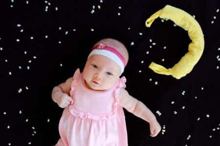 Beautiful baby girl with a moon and sky background