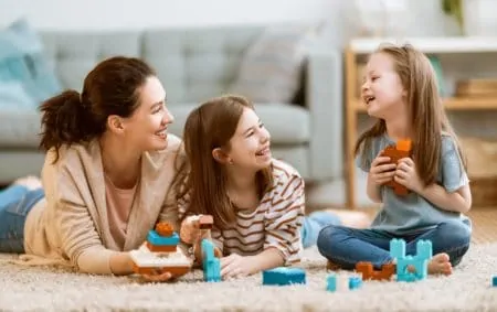 Happy mom and daughters play with lego sets