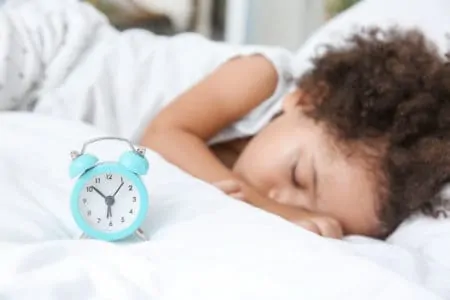 Little toddler sleeping with an alarm clock