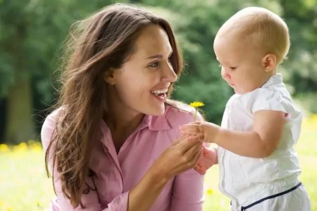 Happy mother giving flower to baby