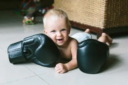 Happy smiling little baby boy with boxing gloves