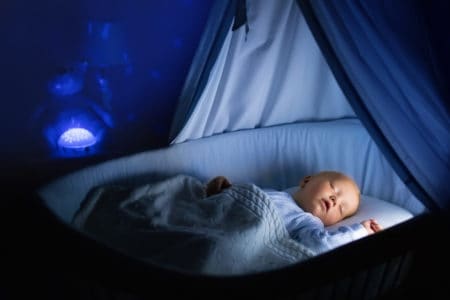 Cute baby soothed to sleep with a night projector