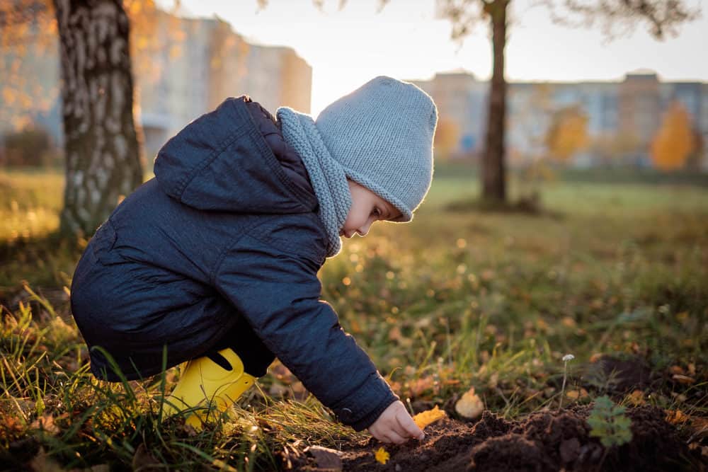 Beautiful toddler playing with earthy soil