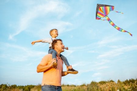 Father and son playing with kite out in the field