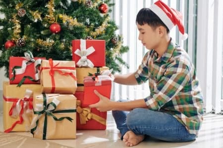Teenage boy opening presents by the Christmas tree