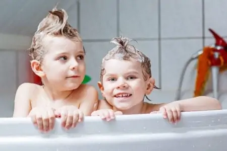 Two little boys shampooing their hair in the bathtub
