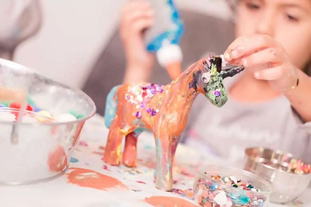 Little girl decorating unicorn paper mache