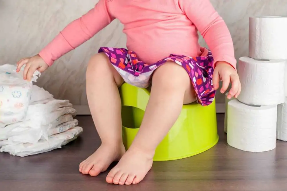 Toddler on a potty training with diapers and tissue rolls