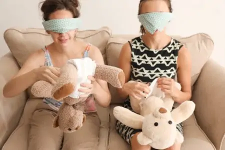 Two women putting diapers on toys at baby shower party