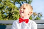 Happy boy dressed in white shirt with red bow tie