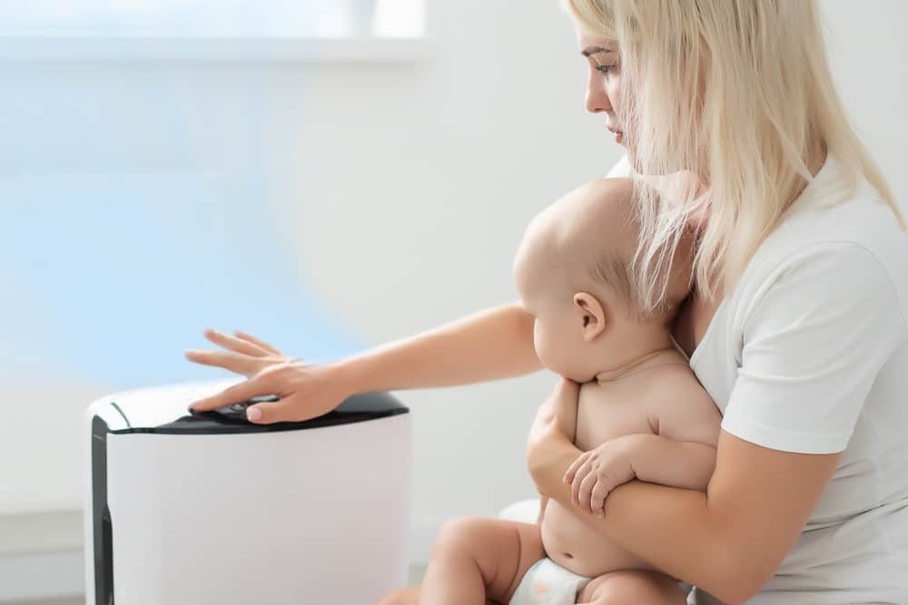 A mother and her child near air purifier in a baby nursery.