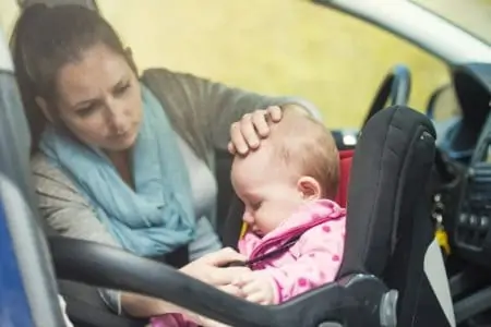 A mother putting her baby in a car seat