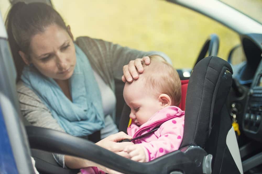 A mother putting her baby in a car seat