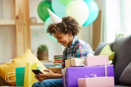 A smiling 16-year-old African American boy opening presents at his birthday party