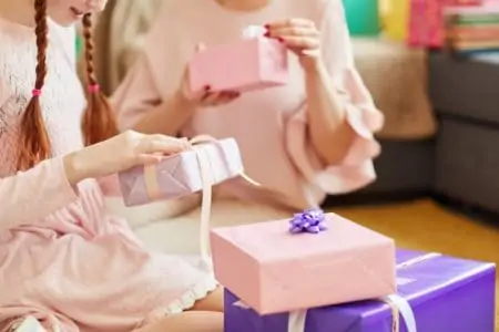 Happy 16-year-old girls opening gifts at a birthday party