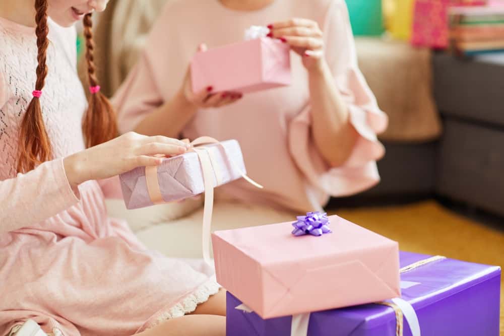 Happy 16-year-old girls opening gifts at a birthday party