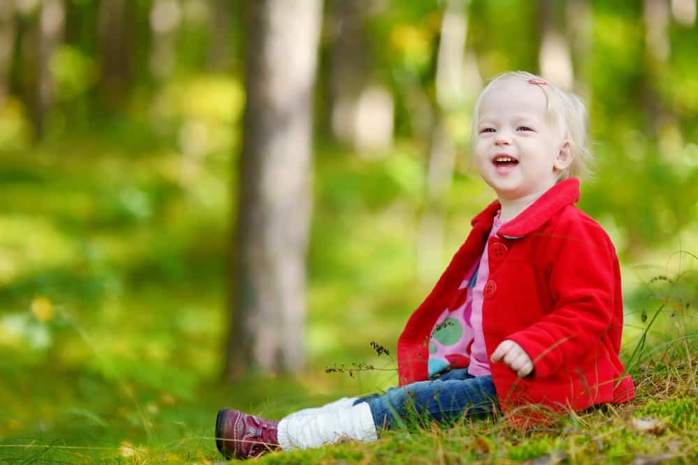 Adorable toddler girl sitting in the forest
