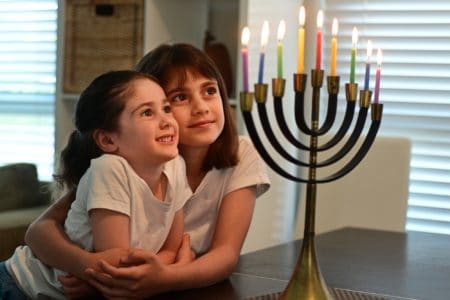 Two Jewish girls looking at the Hanukkah menorah