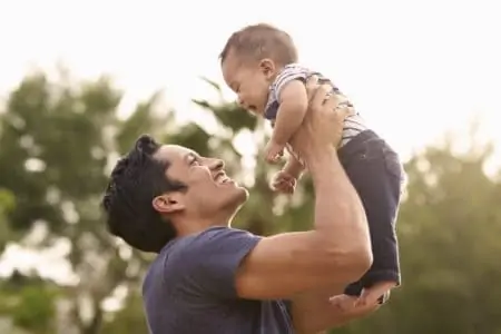 Hispanic father holding his little baby son in the air