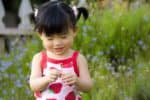 Smiling Chinese girl holding a flower in her hands