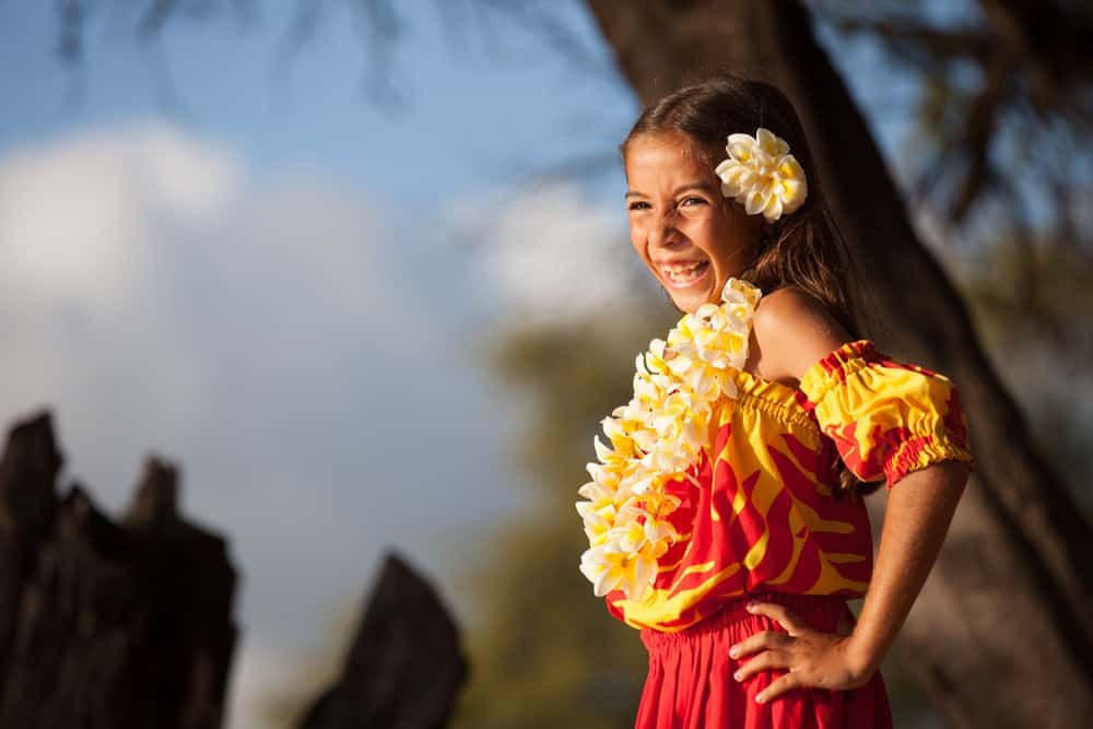 Happy Hawaiian girl wearing a flower lei is standing on the beach