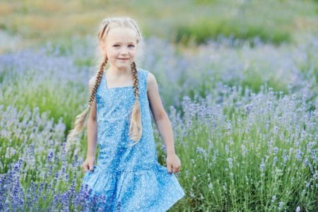 Adorable little girl wearing blue dress in lavender field