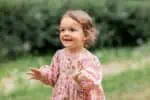 Happy little cute girl wearing pink dress in the park
