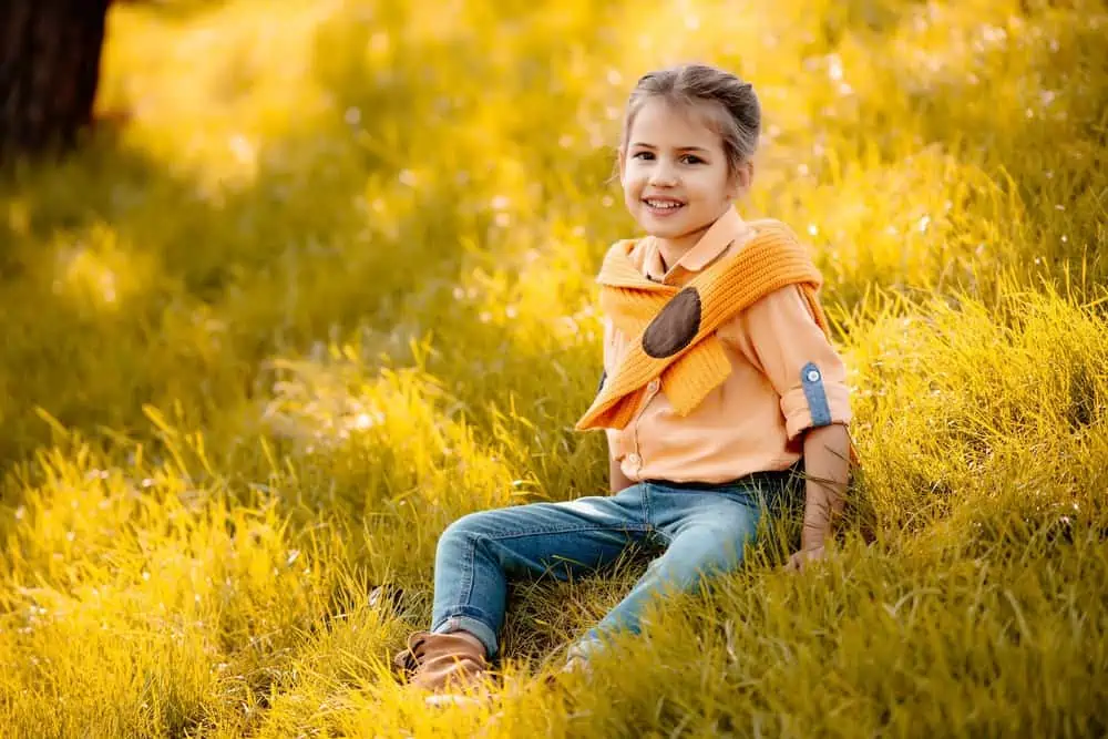 Cheerful girl sitting on the field of autumn grass