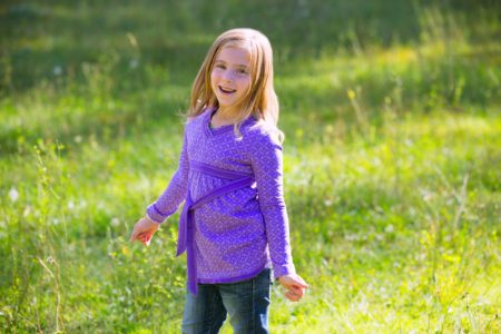 Cheerful little girl in green meadow