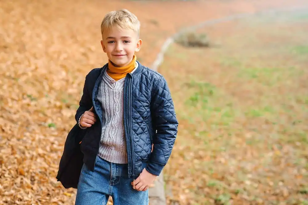 Smiling young blonde boy in the autumn park