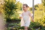 Cheerful little girl wearing white dress in the garden