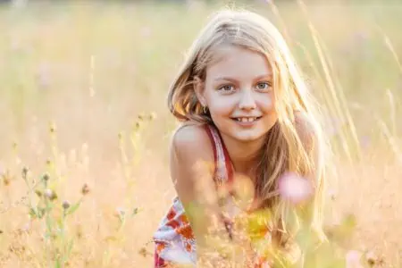 Cheerful little girl playing in the meadow