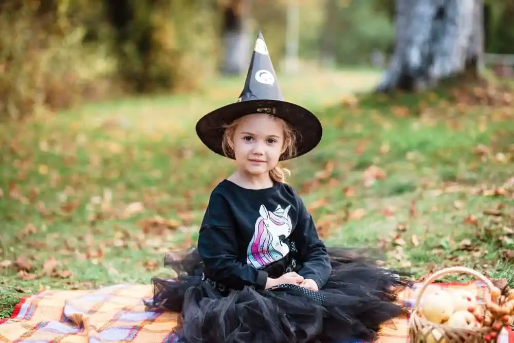 Cute little girl in a Halloween costume sitting in the park