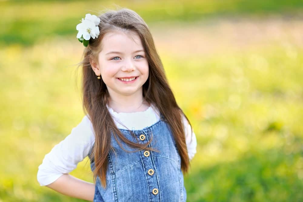 Smiling little girl with a flower hair clip spending time outdoors