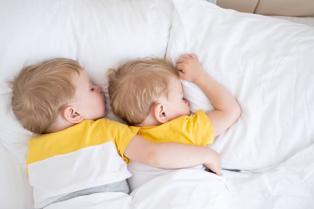 Two little twin boys sleeping in the bed