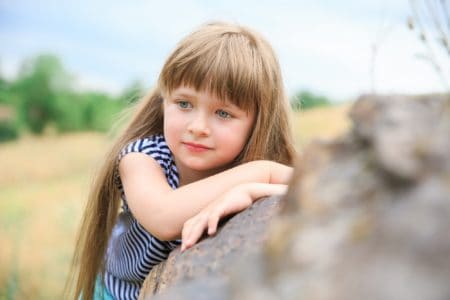Adorable little girl leaning on rock