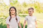 Smiling young boy looking at beautiful girl while holding hands in the park