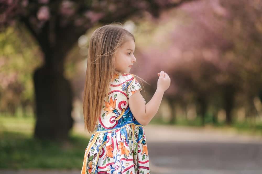 Adorable young girl in dress poses outdoors