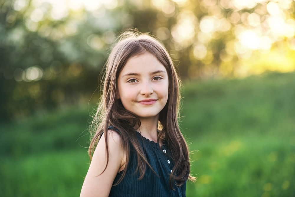 Beautiful smiling little girl standing outside in meadow